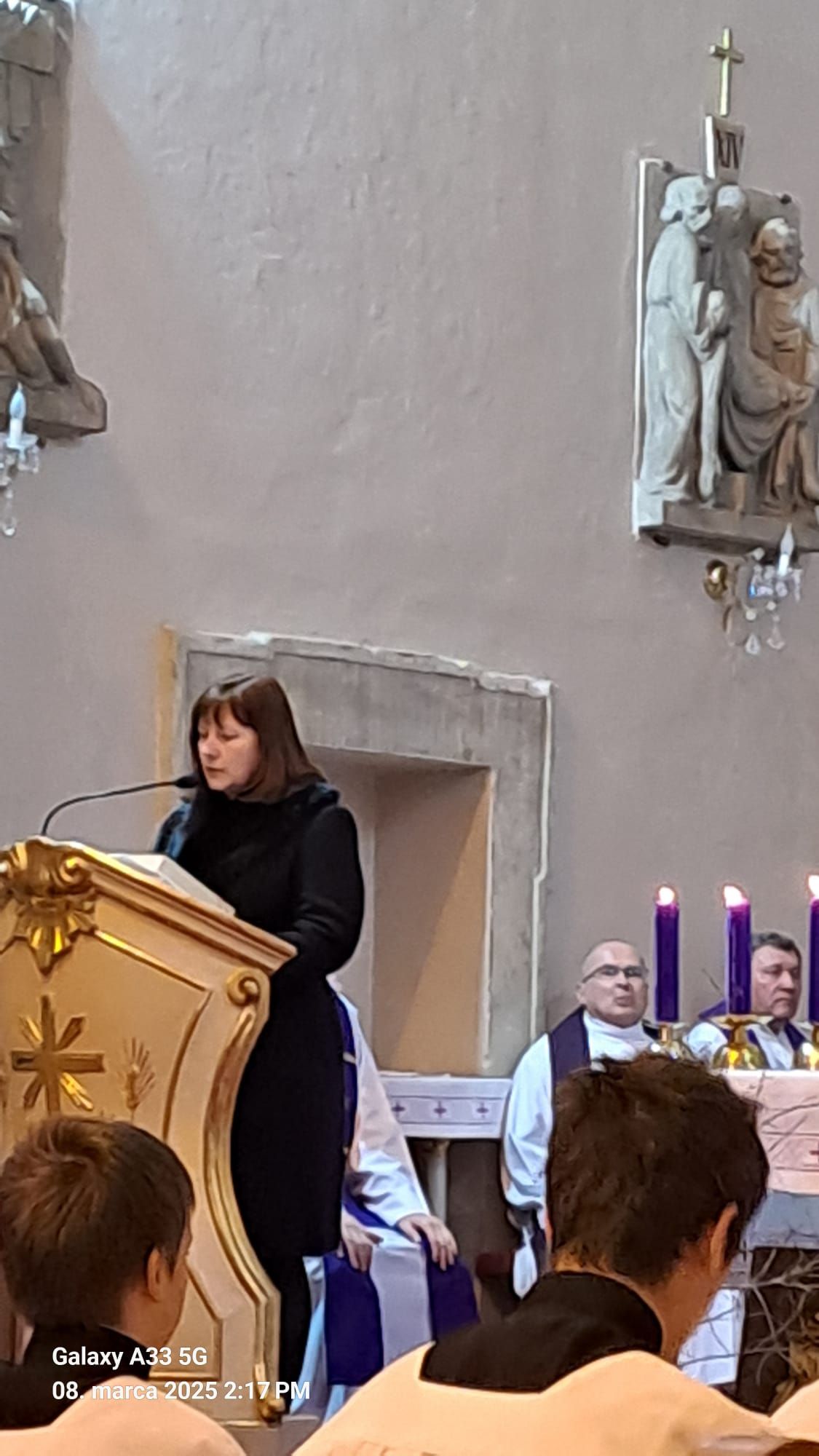 Pohľad do interiéru kostola počas pohrebnej omše Mons. Mariána Feduša v Rišňovciach, 8. marca 2025. Okolo oltára kňazi v liturgických rúchach fialovej farby a miništranti, na pozadí oltár s bohatou výzdobou a svietiacim lustrom nad ním.